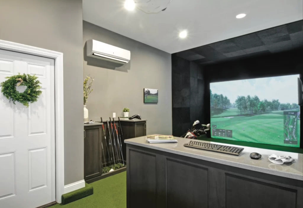 A view of a garage golf simulator with an AC and monitor